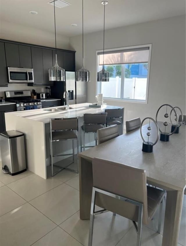 7740 Sandy Ridge Dr Unit 102, Reunion, FL 34747 - kitchen with appliances with stainless steel finishes, light tile patterned flooring, dark cabinetry, and pendant lighting