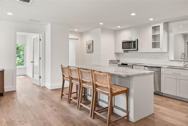91 Minnehaha Cir, Maitland, FL 32751 - kitchen with stainless steel appliances, light stone counters, a kitchen breakfast bar, recessed lighting, and light wood-type flooring