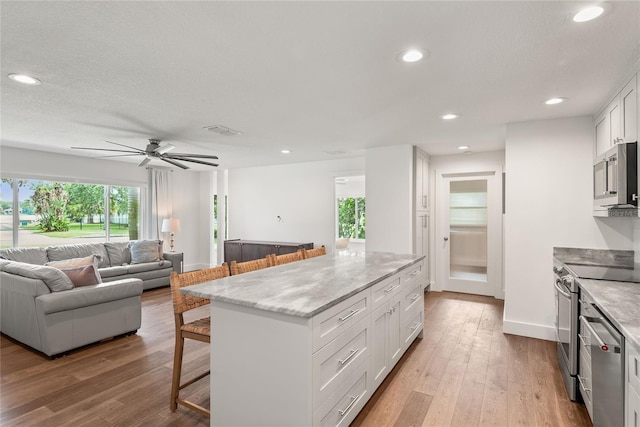 91 Minnehaha Cir, Maitland, FL 32751 - kitchen featuring appliances with stainless steel finishes, a kitchen breakfast bar, a ceiling fan, white cabinetry, and a kitchen island