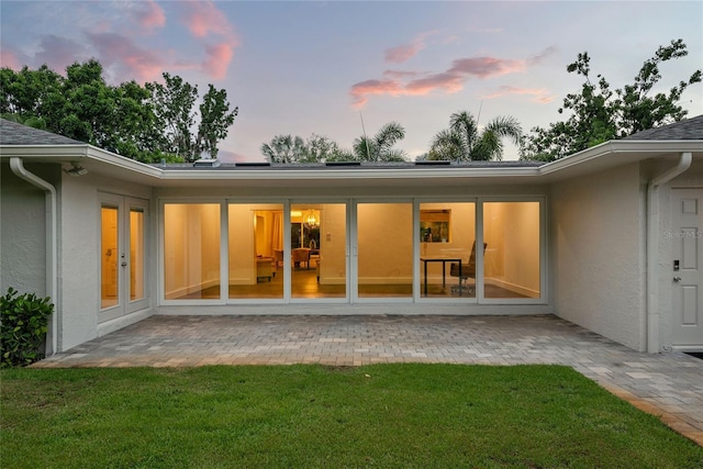 91 Minnehaha Cir, Maitland, FL 32751 - back of property at dusk featuring stucco siding, a patio, and a lawn