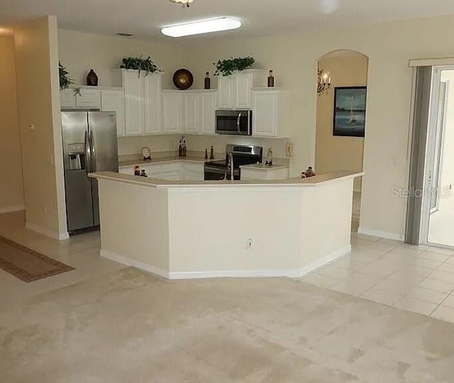 37 Ethan Allen Dr, Palm Coast, FL 32164 - kitchen with appliances with stainless steel finishes, arched walkways, white cabinets, and light tile patterned flooring