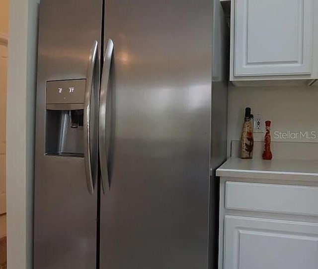 37 Ethan Allen Dr, Palm Coast, FL 32164 - detailed view of stainless steel fridge with ice dispenser, white cabinetry, and light countertops