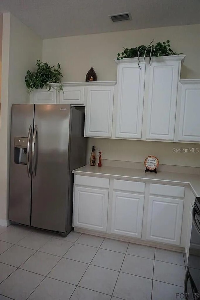37 Ethan Allen Dr, Palm Coast, FL 32164 - kitchen with stainless steel fridge, light tile patterned floors, light countertops, and white cabinets