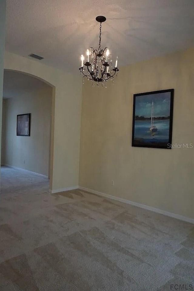 37 Ethan Allen Dr, Palm Coast, FL 32164 - spare room featuring arched walkways, a chandelier, and carpet flooring