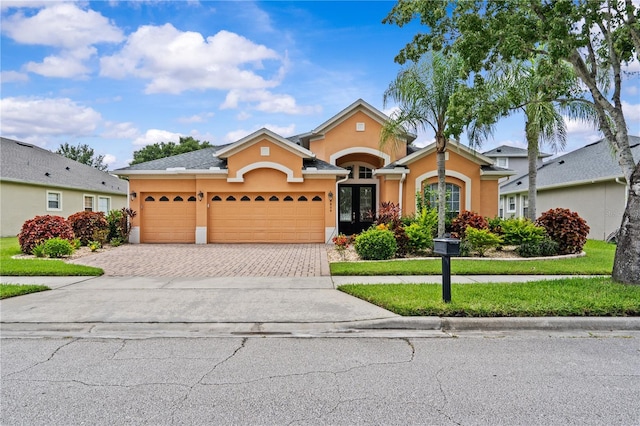 8804 Warwick Shore Xing Unit X, Orlando, FL 32829 - view of front of home with stucco siding, driveway, french doors, a garage, and a front lawn