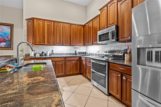 8804 Warwick Shore Xing Unit X, Orlando, FL 32829 - kitchen with appliances with stainless steel finishes, light tile patterned floors, decorative backsplash, dark stone counters, and brown cabinets