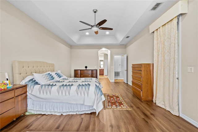 8804 Warwick Shore Xing Unit X, Orlando, FL 32829 - bedroom featuring wood finished floors, arched walkways, a raised ceiling, recessed lighting, and ceiling fan