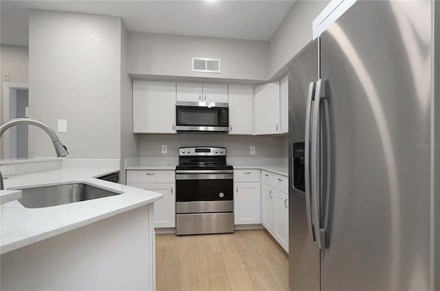 826 Camargo Way Unit 201, Altamonte Springs, FL 32714 - kitchen with stainless steel appliances, white cabinetry, light wood-style floors, and light stone counters