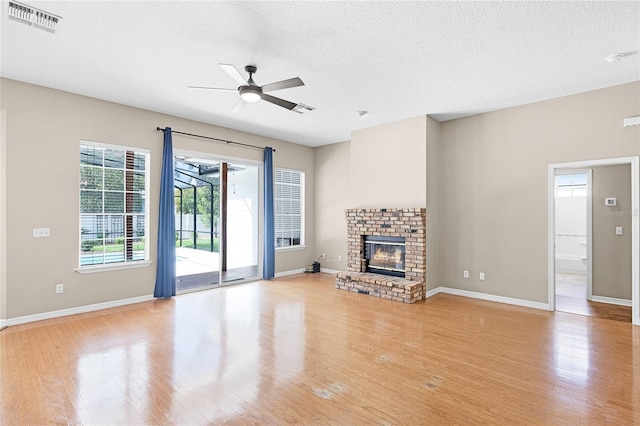 403 Courtlea Creek Dr, Winter Garden, FL 34787 - unfurnished living room featuring ceiling fan, light wood-type flooring, a brick fireplace, and a textured ceiling