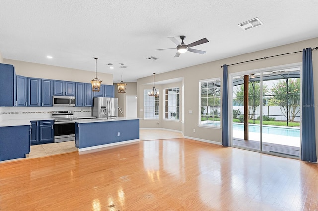 403 Courtlea Creek Dr, Winter Garden, FL 34787 - kitchen featuring stainless steel appliances, blue cabinets, light countertops, ceiling fan, and light wood-type flooring