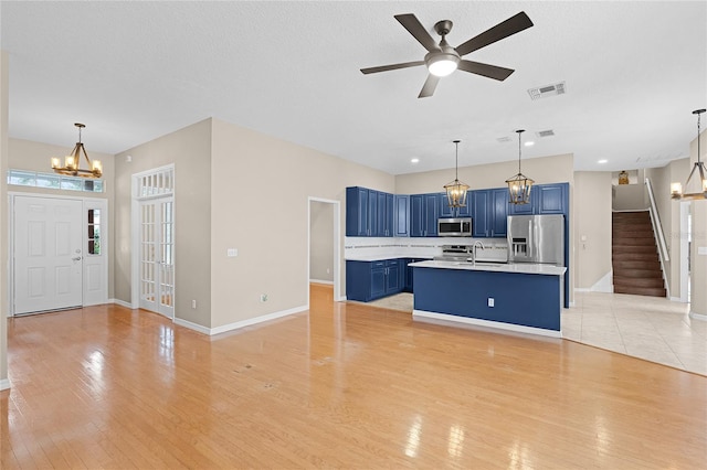 403 Courtlea Creek Dr, Winter Garden, FL 34787 - kitchen featuring stainless steel appliances, blue cabinetry, light countertops, light wood finished floors, and a chandelier