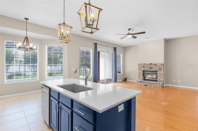 403 Courtlea Creek Dr, Winter Garden, FL 34787 - kitchen with blue cabinetry, a chandelier, stainless steel dishwasher, a fireplace, and ceiling fan