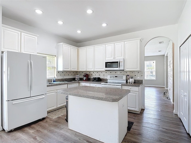 799 Hacienda Cir, Kissimmee, FL 34741 - kitchen featuring white appliances, arched walkways, white cabinets, a center island, and recessed lighting