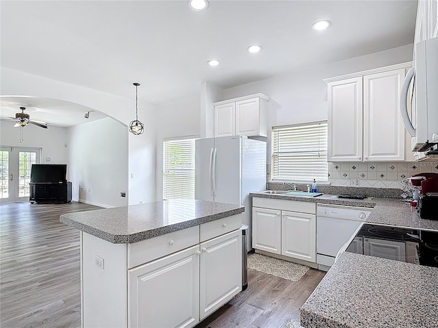 799 Hacienda Cir, Kissimmee, FL 34741 - kitchen featuring a ceiling fan, arched walkways, white appliances, light wood-style flooring, and backsplash