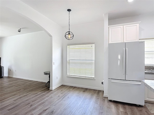 799 Hacienda Cir, Kissimmee, FL 34741 - kitchen featuring freestanding refrigerator, arched walkways, white cabinets, wood finished floors, and hanging light fixtures