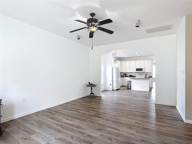 799 Hacienda Cir, Kissimmee, FL 34741 - unfurnished living room with arched walkways, dark wood-style floors, and a ceiling fan