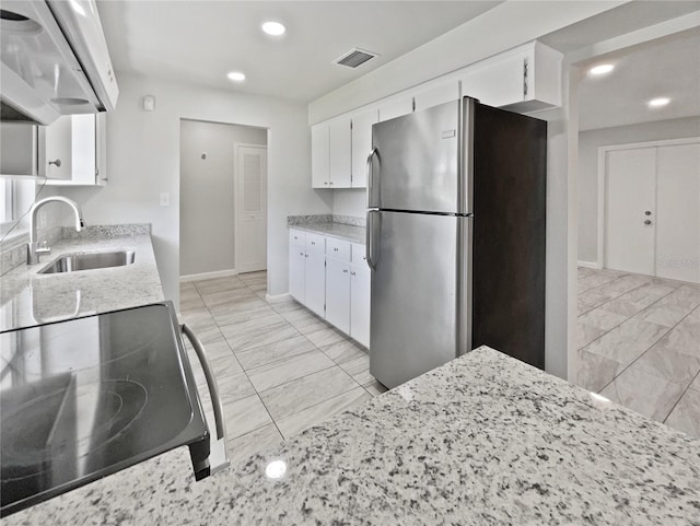2607 Castle Oak Ave, Orlando, FL 32808 - kitchen featuring freestanding refrigerator, extractor fan, electric stove, light marble finish floors, and white cabinetry