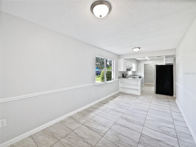 2607 Castle Oak Ave, Orlando, FL 32808 - kitchen featuring freestanding refrigerator, a textured ceiling, white cabinetry, light countertops, and a peninsula