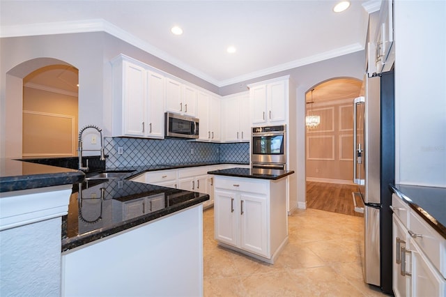 2258 Rickover Pl, Winter Garden, FL 34787 - kitchen with appliances with stainless steel finishes, arched walkways, tasteful backsplash, dark stone counters, and white cabinets
