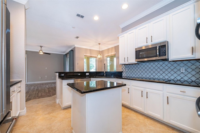 2258 Rickover Pl, Winter Garden, FL 34787 - kitchen with stainless steel microwave, a peninsula, black cooktop, white cabinetry, and tasteful backsplash