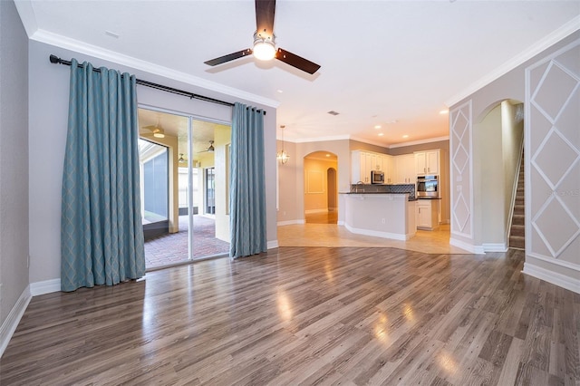 2258 Rickover Pl, Winter Garden, FL 34787 - unfurnished living room with arched walkways, ceiling fan, light wood-type flooring, crown molding, and stairway
