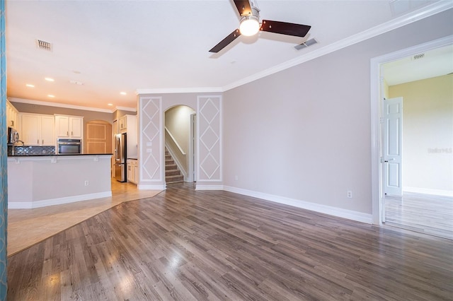 2258 Rickover Pl, Winter Garden, FL 34787 - unfurnished living room with arched walkways, light wood-style floors, ceiling fan, ornamental molding, and stairway