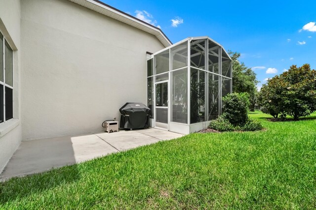 785 Hawks Blf, Clermont, FL 34711 - back of house with stucco siding, a lawn, glass enclosure, and a patio