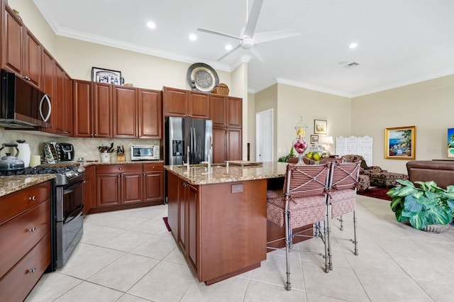 785 Hawks Blf, Clermont, FL 34711 - kitchen with appliances with stainless steel finishes, crown molding, a center island with sink, decorative backsplash, and a breakfast bar area
