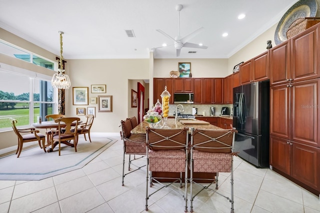 785 Hawks Blf, Clermont, FL 34711 - kitchen featuring black fridge with ice dispenser, stainless steel microwave, light tile patterned floors, a chandelier, and decorative backsplash