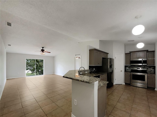 1726 Sunset Ridge Dr, Mascotte, FL 34753 - kitchen featuring appliances with stainless steel finishes, backsplash, tile patterned flooring, a peninsula, and dark stone counters