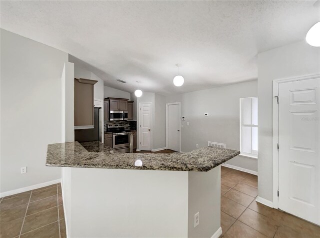 1726 Sunset Ridge Dr, Mascotte, FL 34753 - kitchen with appliances with stainless steel finishes, dark tile patterned flooring, stone counters, tasteful backsplash, and a textured ceiling