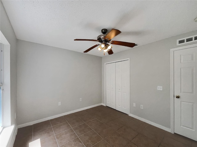 1726 Sunset Ridge Dr, Mascotte, FL 34753 - unfurnished bedroom featuring dark tile patterned flooring, a closet, ceiling fan, and a textured ceiling