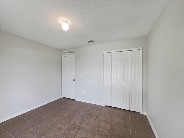 1726 Sunset Ridge Dr, Mascotte, FL 34753 - unfurnished bedroom with a textured ceiling, a closet, and dark tile patterned flooring