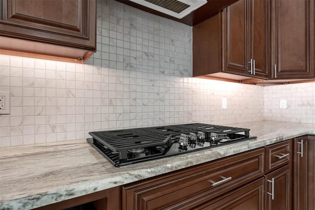 9342 Bay Vista Estates Blvd, Orlando, FL 32836 - kitchen with black gas stovetop, decorative backsplash, dark brown cabinets, light stone counters, and ventilation hood
