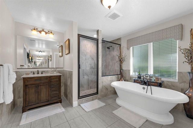 9342 Bay Vista Estates Blvd, Orlando, FL 32836 - bathroom featuring tile walls, a stall shower, a soaking tub, vanity, and a wainscoted wall