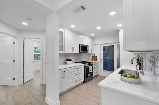 610 Huntly Ln, Winter Springs, FL 32708 - kitchen with stainless steel appliances, decorative backsplash, white cabinetry, light wood finished floors, and recessed lighting