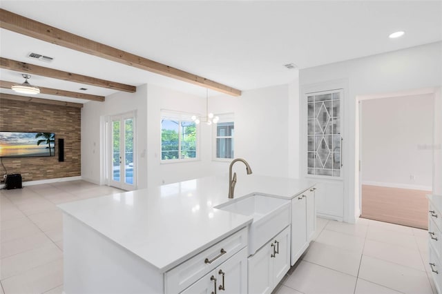 2540 Wembleycross Way, Orlando, FL 32828 - kitchen featuring light tile patterned floors, beamed ceiling, white cabinetry, open floor plan, and light countertops
