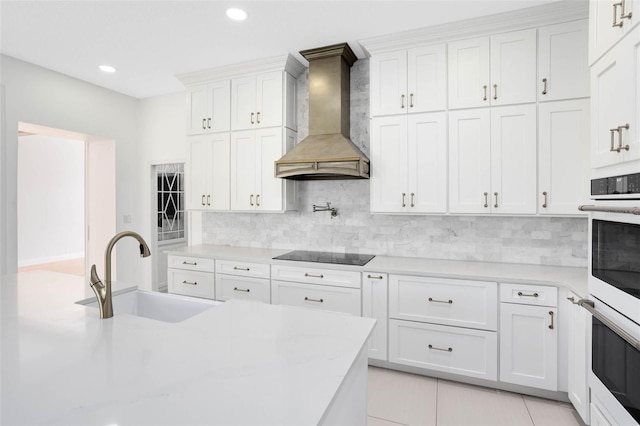 2540 Wembleycross Way, Orlando, FL 32828 - kitchen with custom range hood, black electric stovetop, decorative backsplash, white cabinetry, and recessed lighting