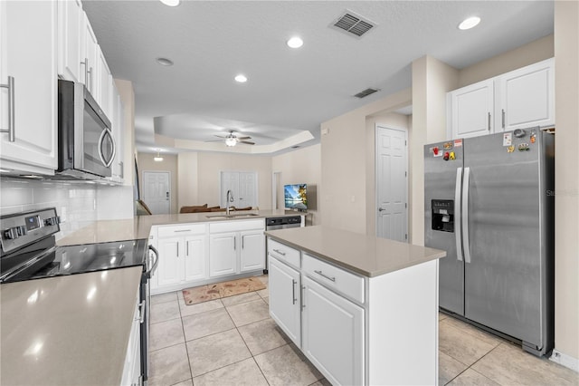 3443 Sagebrush St, Harmony, FL 34773 - kitchen with appliances with stainless steel finishes, a ceiling fan, a peninsula, white cabinets, and light tile patterned floors