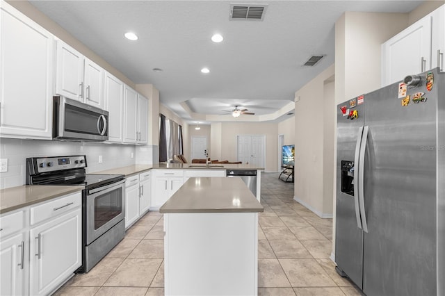 3443 Sagebrush St, Harmony, FL 34773 - kitchen featuring stainless steel appliances, a peninsula, a kitchen island, ceiling fan, and white cabinets