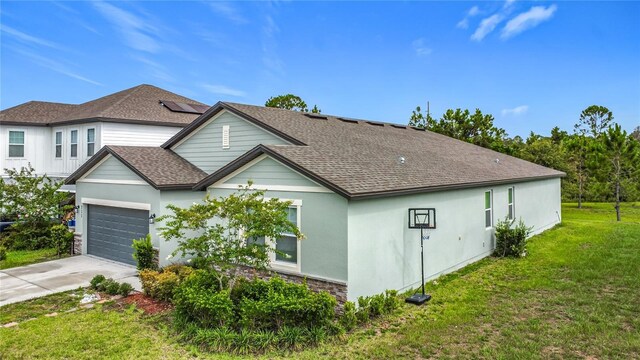 711 Steerview St, Saint Cloud, FL 34771 - view of side of property with concrete driveway, a lawn, roof with shingles, solar panels, and an attached garage