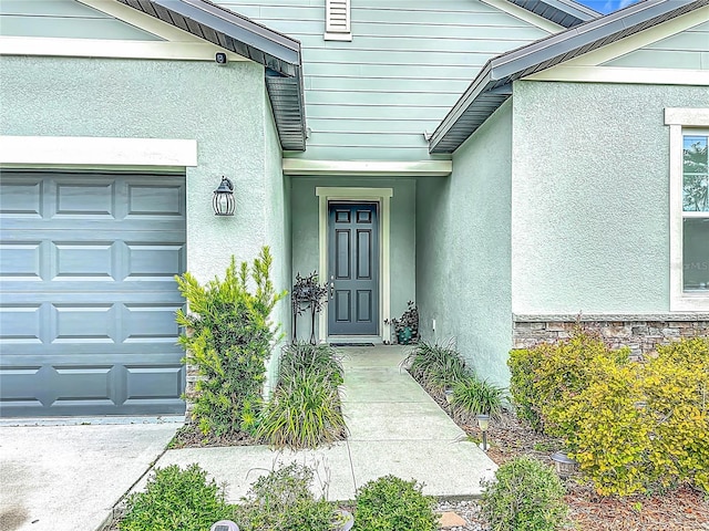 711 Steerview St, Saint Cloud, FL 34771 - view of exterior entry with an attached garage, stucco siding, and stone siding