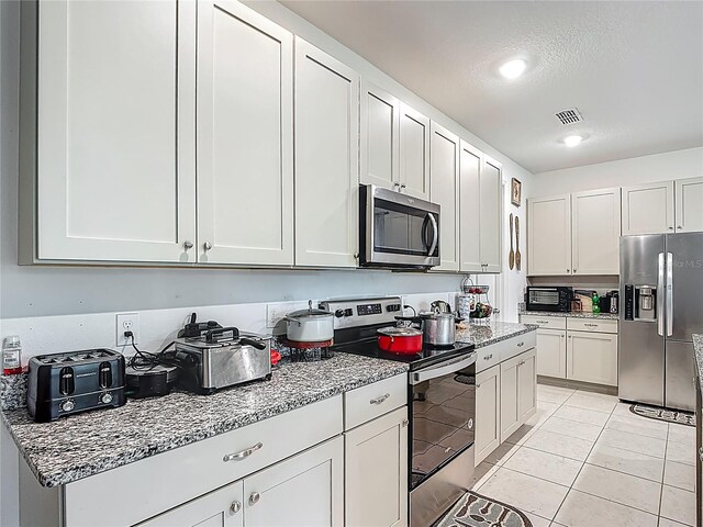 711 Steerview St, Saint Cloud, FL 34771 - kitchen with appliances with stainless steel finishes, light stone countertops, light tile patterned floors, and white cabinets