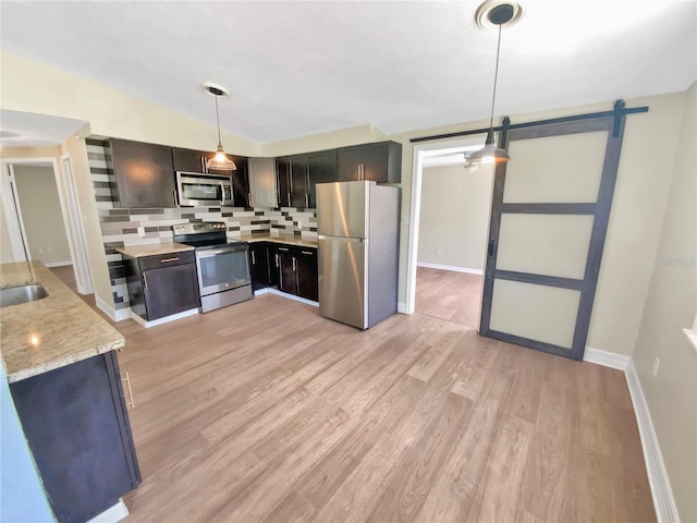 4233 Las Vegas Dr, New Port Richey, FL 34653 - kitchen featuring stainless steel appliances, a barn door, backsplash, light wood-type flooring, and light stone counters
