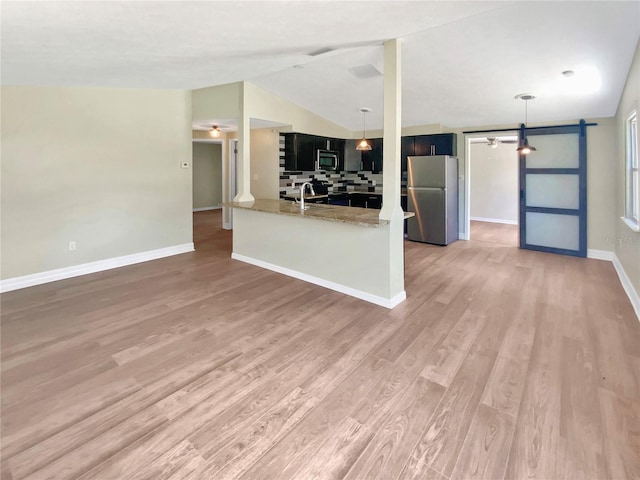4233 Las Vegas Dr, New Port Richey, FL 34653 - kitchen featuring appliances with stainless steel finishes, light wood-type flooring, tasteful backsplash, lofted ceiling, and dark cabinets