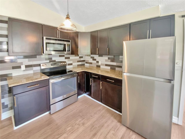 4233 Las Vegas Dr, New Port Richey, FL 34653 - kitchen with stainless steel appliances, backsplash, light stone countertops, light wood-style flooring, and hanging light fixtures