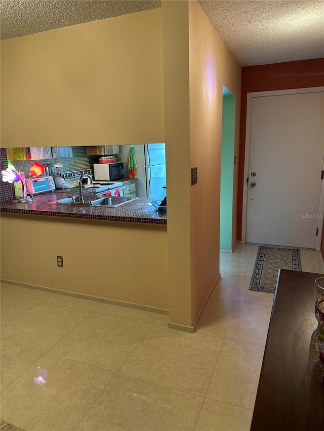 3279 Westridge Blvd Unit 204, Orlando, FL 32822 - kitchen featuring a textured ceiling, dark countertops, freestanding refrigerator, and decorative backsplash