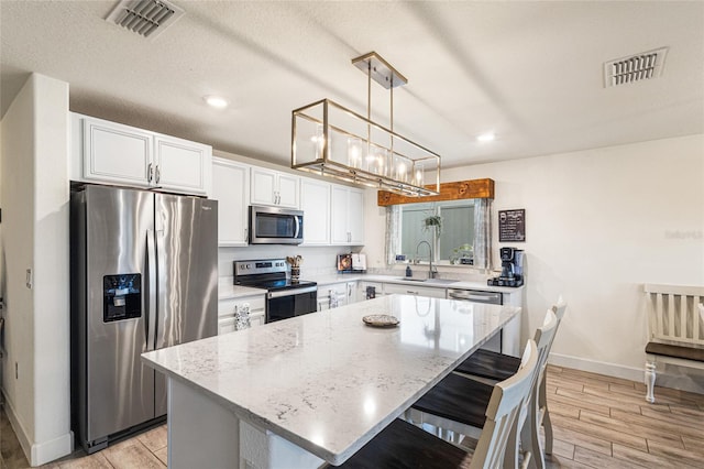 1668 Wilson Prairie Cir, Groveland, FL 34736 - kitchen featuring stainless steel appliances, a center island, white cabinets, light wood finished floors, and recessed lighting