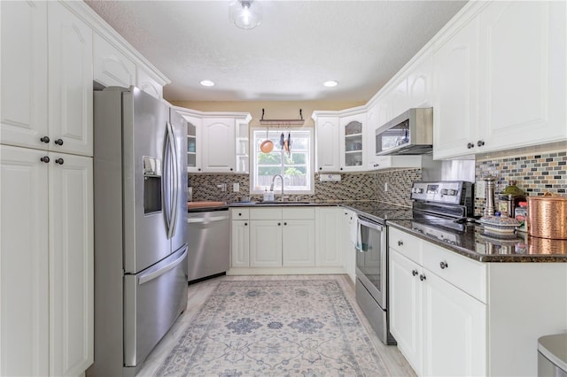 5361 Jade Cir, Belle Isle, FL 32812 - kitchen featuring stainless steel appliances, glass insert cabinets, backsplash, white cabinets, and dark stone counters