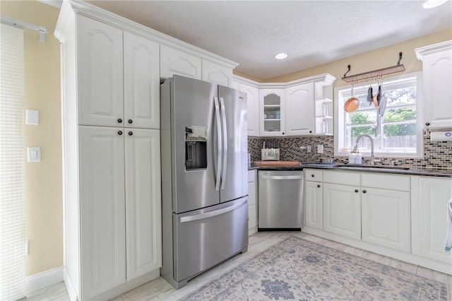 5361 Jade Cir, Belle Isle, FL 32812 - kitchen featuring appliances with stainless steel finishes, dark countertops, decorative backsplash, white cabinets, and glass insert cabinets